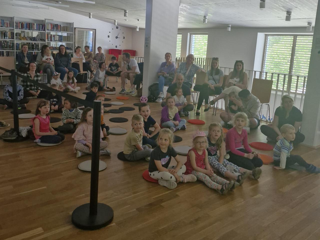 die Kinder und Erwachsenen sitzen und lauschen der Geschichte