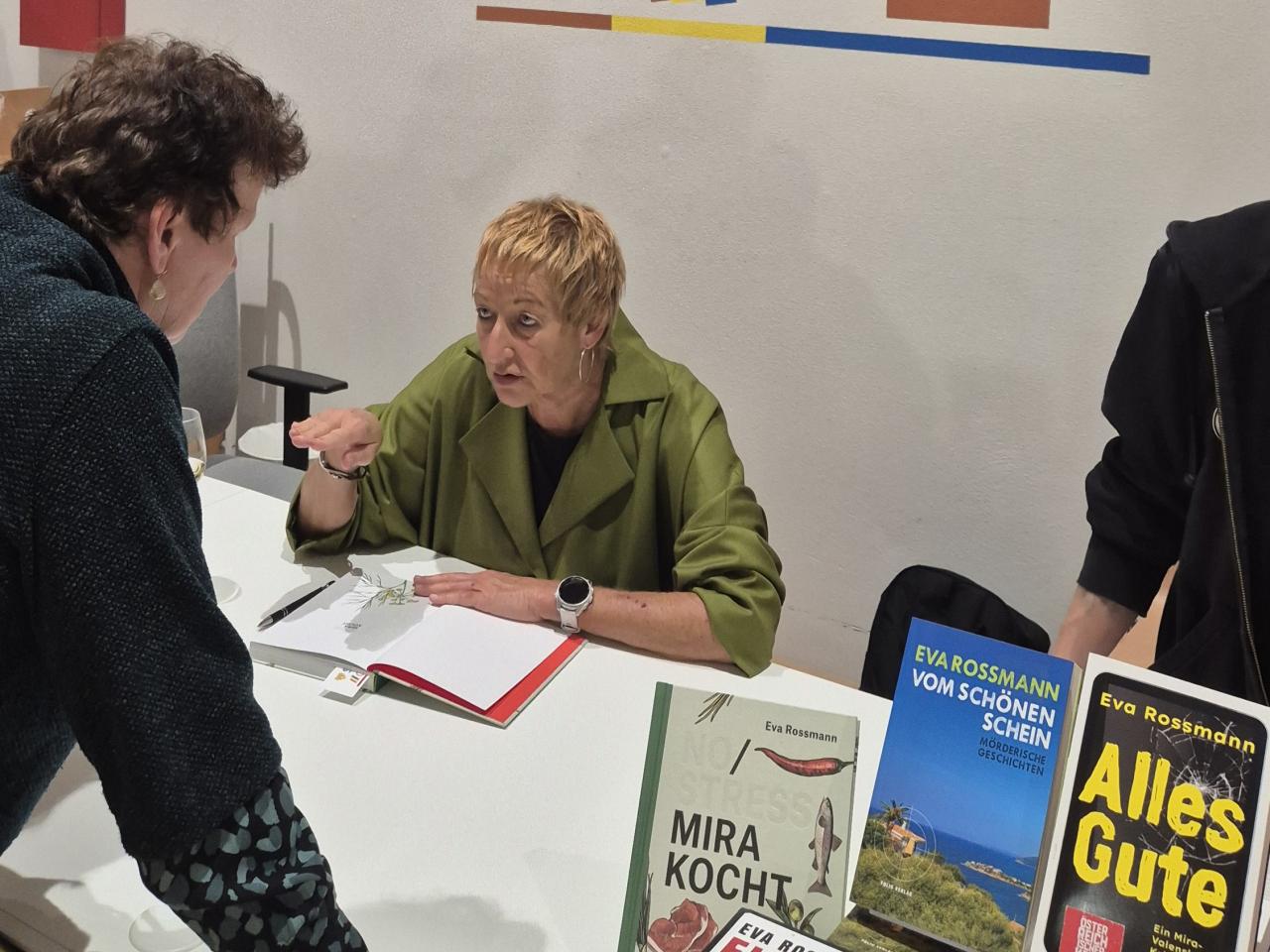 die Autorin erzählt einer Leserin, im Vordergrund ihre Bücher