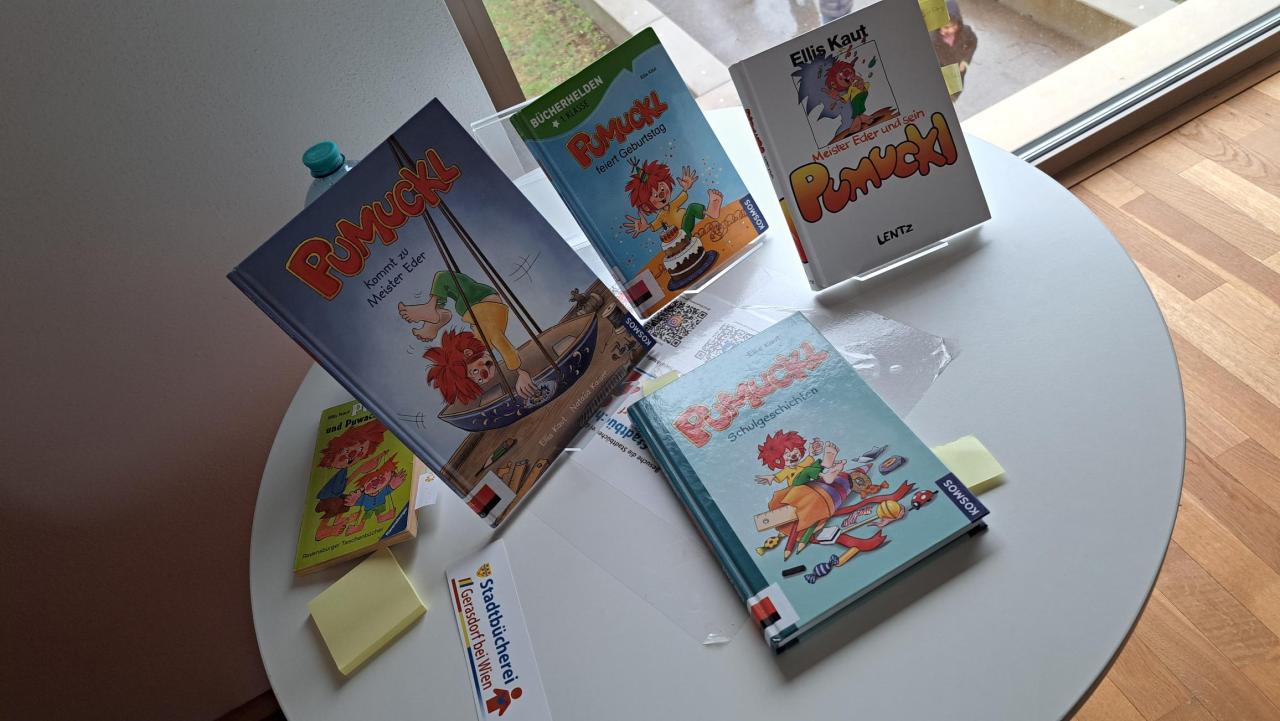 ein runder Tisch auf dem einige Bücher stehen, ein Buch liegt