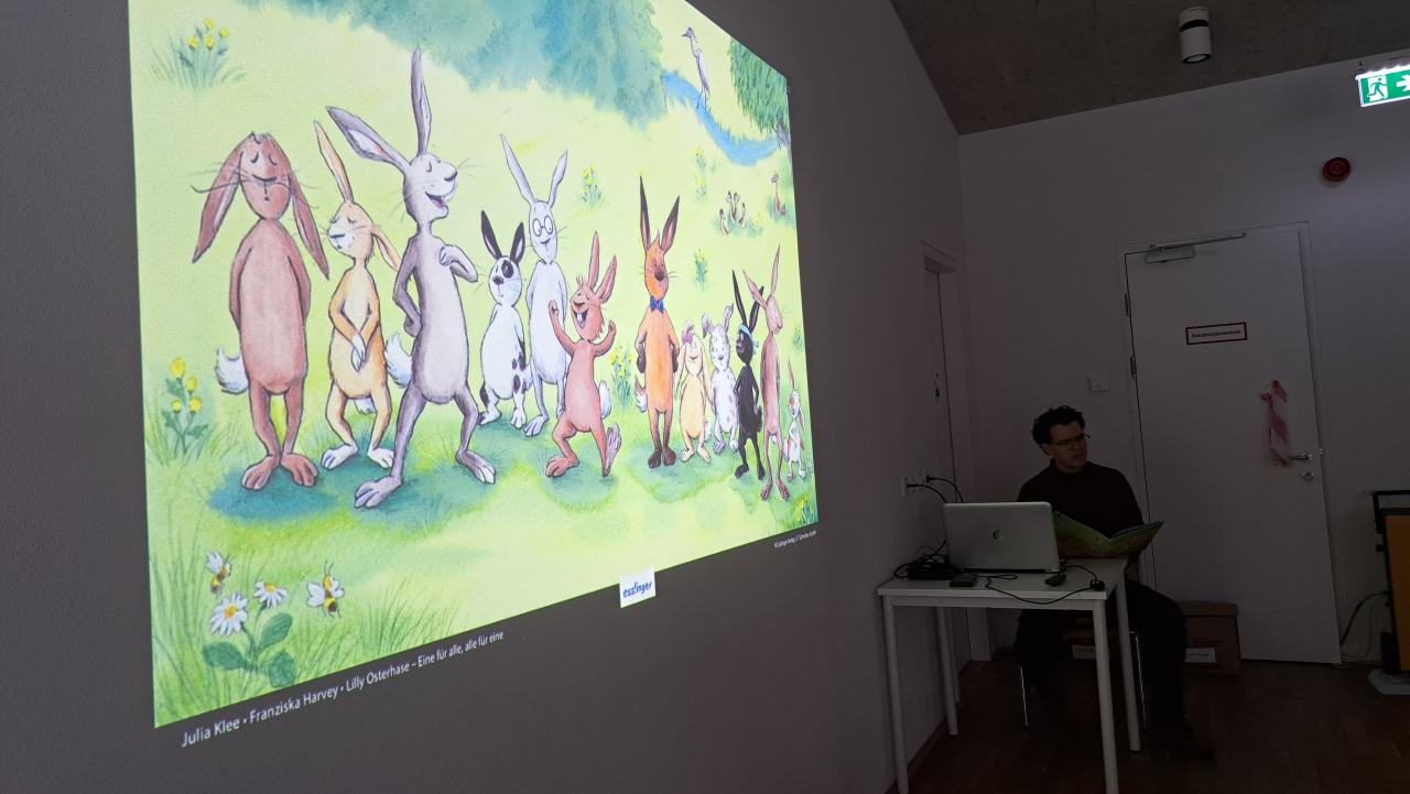 ein Mann sitzt und liest, auf der Wand das Bild dazu