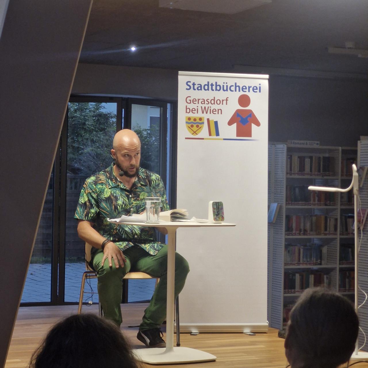 ein Mann sitzt auf der Bühne und schaut ins Publikum